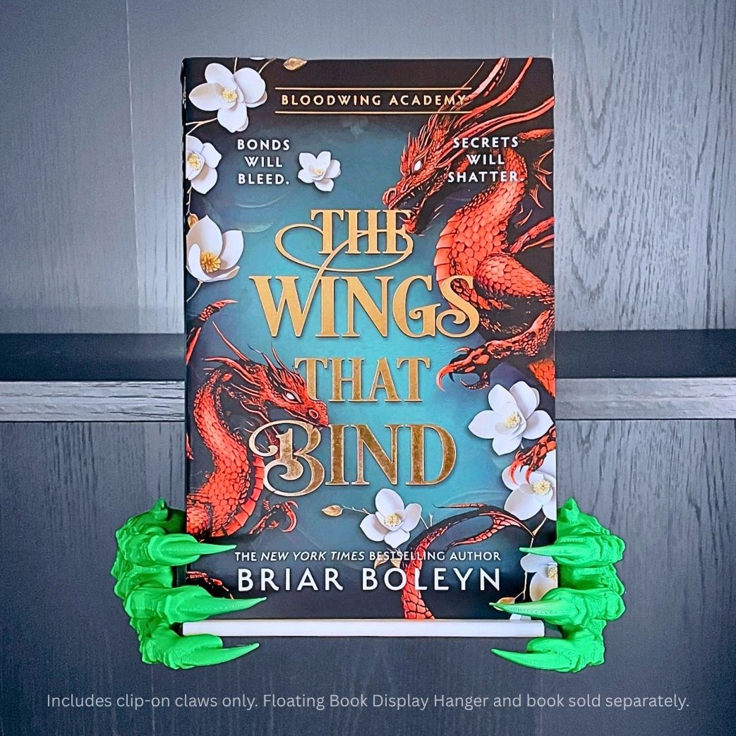 Green 3D printed Dragon Claws Curio Clip-Ons framing the fantasy book The Wings That Bind by Briar Boleyn, clipped onto a Curio Candy Floating Book Display Hanger.